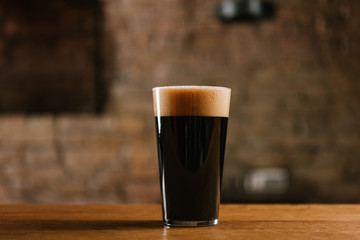 close-up view of fresh cold beer with foam in glass on wooden table