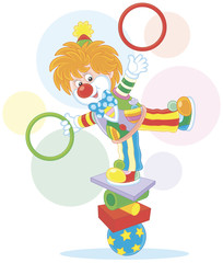 Circus show of a comic juggler - equilibrist. Friendly smiling clown balancing on several objects and juggling with hoops