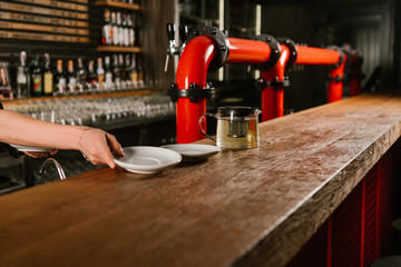 cropped shot of person putting empty plates on wooden bar counter