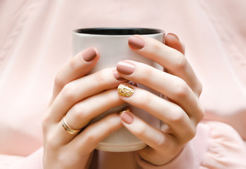 Female hands with beige nail design.