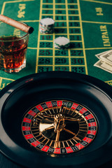 Casino table with roulette and glass with whiskey and cigar
