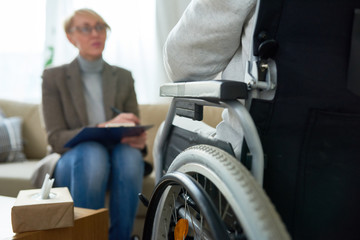 Portrait of  female psychiatrist interviewing handicapped  man during therapy session, copy space