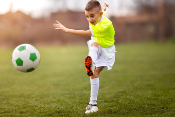Obraz premium Boy kicking football on the sports field