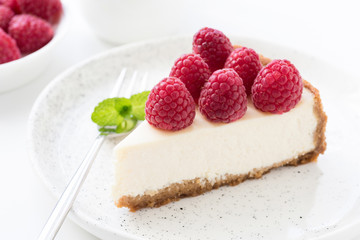 Cheesecake with fresh raspberries on white plate, closeup view