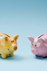 close up view of two yellow and pink piggy banks isolated on blue