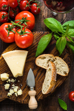Parmesan cheese, ciabatta, basil, fresh tomatoes and glass of red wine. Italian food, italian cuisine. Top view