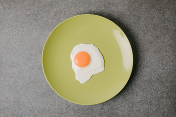 top view of fresh tasty fried egg on plate on grey