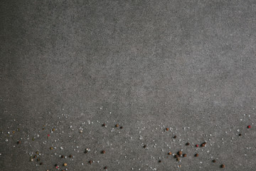 salt and peppercorns scattered on grey background