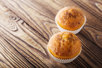 Classic muffins on a wooden old background in a white wrapper.