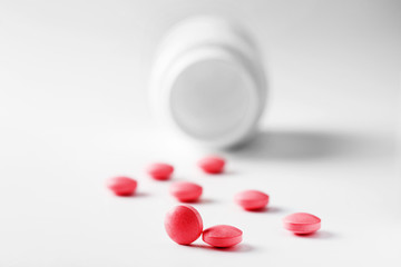 Medical red pills and white bottle on white light background. Concept of healthcare and medicine.