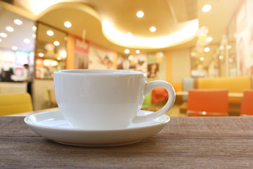 White Coffee cup on wooden table in coffee shop blur background.