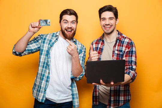 Portrait of a two excited young men holding laptop