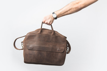 partial view of man holding leather bag in hand isolated on white