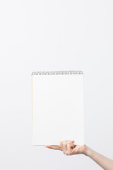 partial view of woman holding blank sketchbook in hand isolated on white