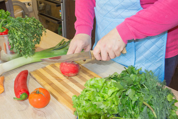 woman cooking healthy meal in the kitchen. Cooking healthy food at home. Woman in kitchen preparing vegetables. Chef cuts the vegetables into a meal