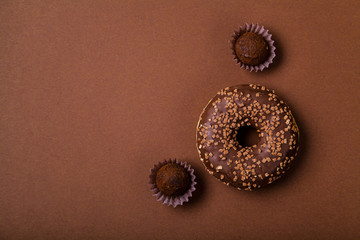 Chocolate donuts with chocolate truffles on brown background. Monochromatic concept.