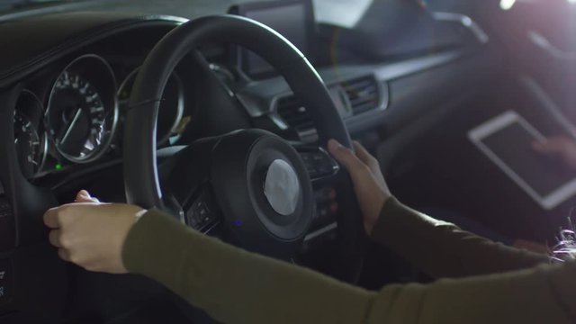 Medium shot of woman inspecting steering wheel and dashboard of car at dealership before making purchase