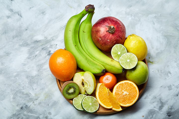 Ripe fresh fruits in a wooden plate on a light background, selective focus, close-up, top view