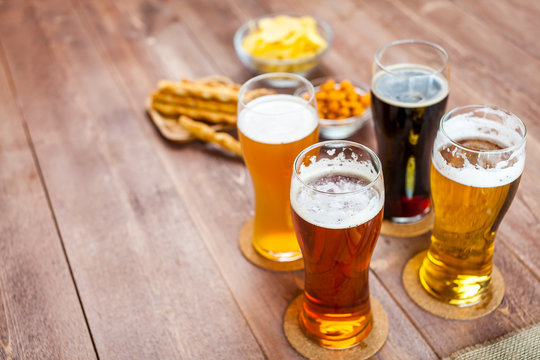 glasses of light and dark beer with assorted snacks on a wooden table background with copy space for text. bachelor party, pub, bar or degustation concept