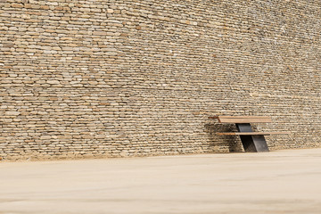 Lonely bench near the stone wall.