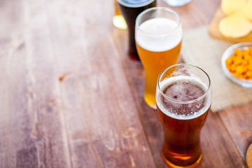 glasses of light and dark beer with assorted snacks on a wooden table background with copy space for text. bachelor party, pub, bar or degustation concept