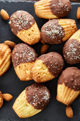 Freshly baked almond cookies with almond on stone board over wooden background, top view, selective focus.