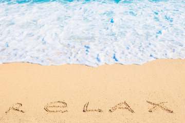 Sea wave washing off relax inscription on sand