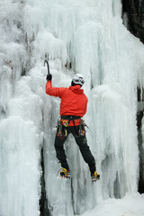 Mann beim Eisklettern