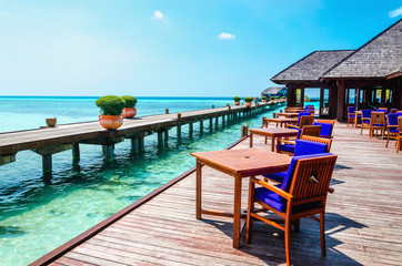 Table and chairs at water restaurant at the background of the blue sky in Maldives island