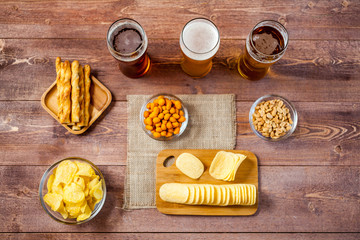 glasses of light and dark beer with assorted snacks on a wooden table background. bachelor party, pub, bar or degustation concept. top view, flat lay