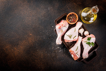 Raw meat, ready for grill or barbeque chicken legs, with herbs and spices n dark rusty background, copy space
