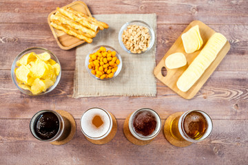 glasses of light and dark beer with assorted snacks on a wooden table background. bachelor party, pub, bar or degustation concept. top view, flat lay