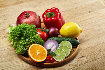 Still life of fresh organic vegetables on wooden plate over wooden background, selective focus, close-up