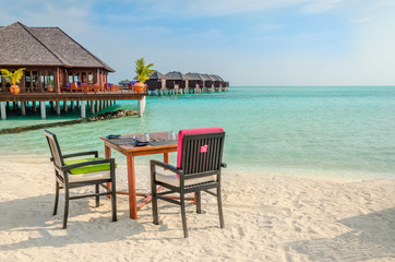 Table and chairs at restaurant at the background of water bungalows, Maldives island
