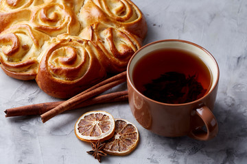 Homemade rose bread, cup of tea, dried citrus and spicies on white textured background, close-up, shallow depth of field