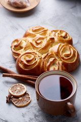 Homemade rose bread, cup of tea, dried citrus and spicies on white textured background, close-up, shallow depth of field