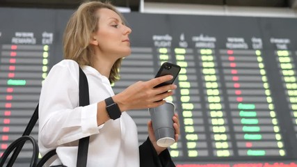 Young Woman At International Airport Checking Flight Information On Phone Application - Powered by Adobe