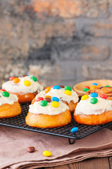 Classic cinnamon rolls - cinnabons with cream cheese frosting with smarties. Wooden background.