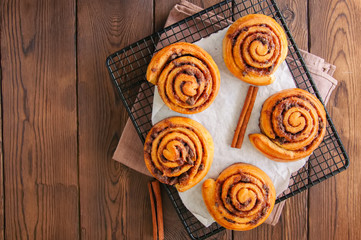 Classic cinnamon rolls - cinnabons on a wire rack. Wooden background.