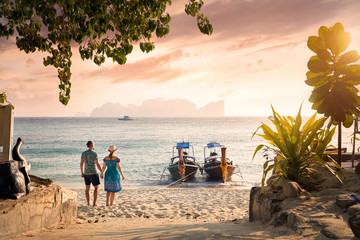 Couple on the tropical sunset beach - obrazy, fototapety, plakaty