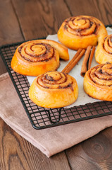Classic cinnamon rolls - cinnabons on a wire rack. Wooden background.