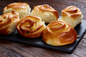Obraz na płótnie Canvas Homemade rose buns on wooden cutting board over rustic vintage background, close-up, shallow depth of field