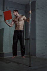 Male acrobat levitates with a book, with his hand he holds on to the pole.