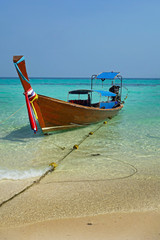 Wooden boat on crystal clear shallow water, Koh Mai Phai island, Thailand