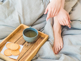 coffee in bed. shapely female legs in warm socks, wooden tray for breakfast in bed. two cups of coffee and marshmallows. the concept of cozy home. top view.