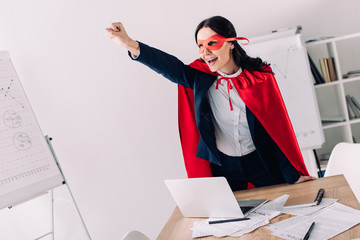 attractive super businesswoman in cape and mask screaming and standing with hand up in office © LIGHTFIELD STUDIOS