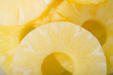 Pieces of pineapple cut into slices in a white plate. Ripe yellow sweet fruit.
