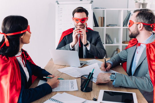 Super Businesspeople In Masks And Capes At Meeting In Office