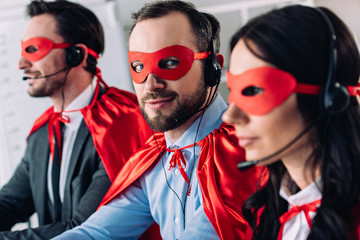 super businesspeople in masks and headsets supporting customers in call center