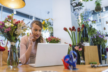 Happy florist using technologies at flower shop